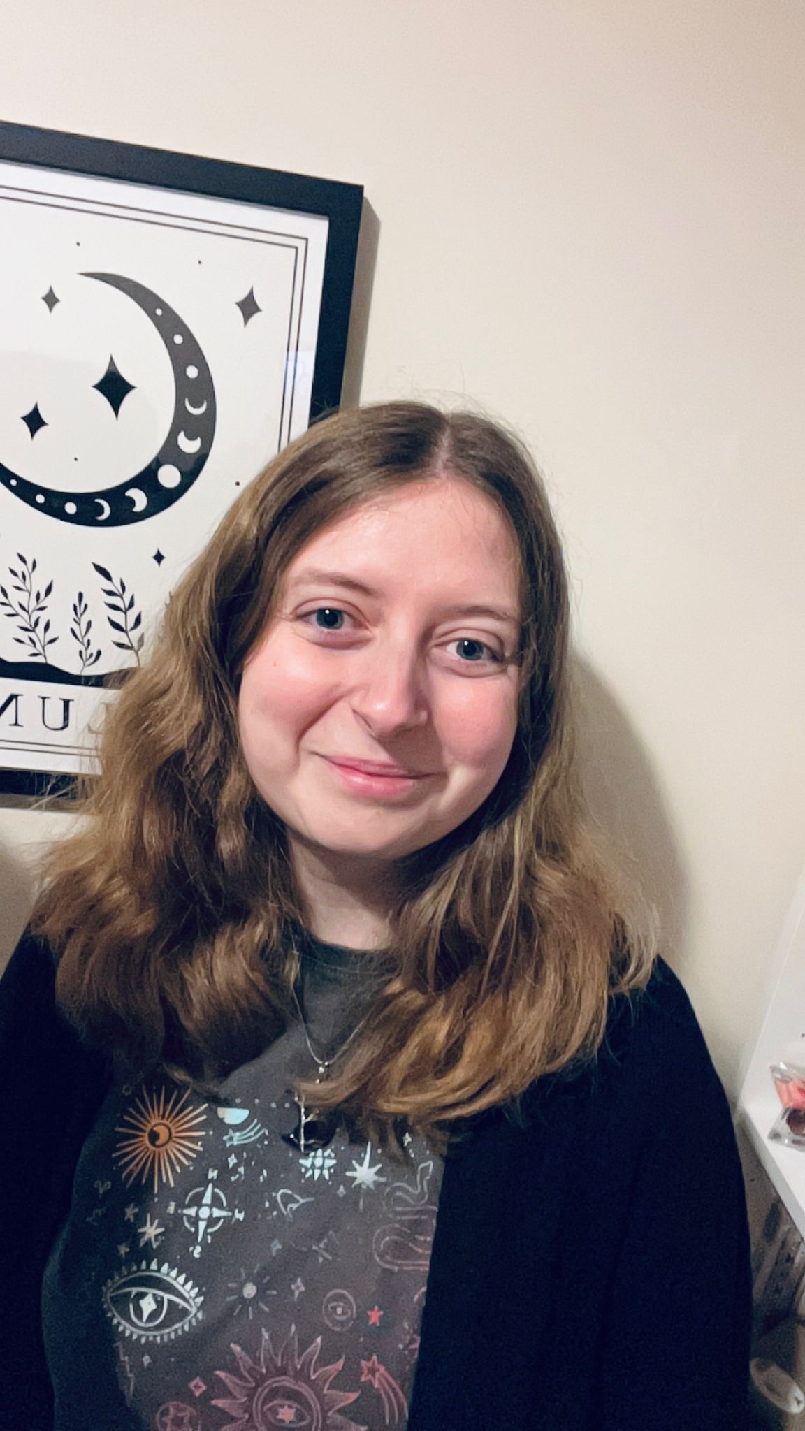 A picture of Grace. Grace is a white woman with brown hair, wearing a dark top and a black cardigan. She is visible from the shoulders up, smiling at the camera.